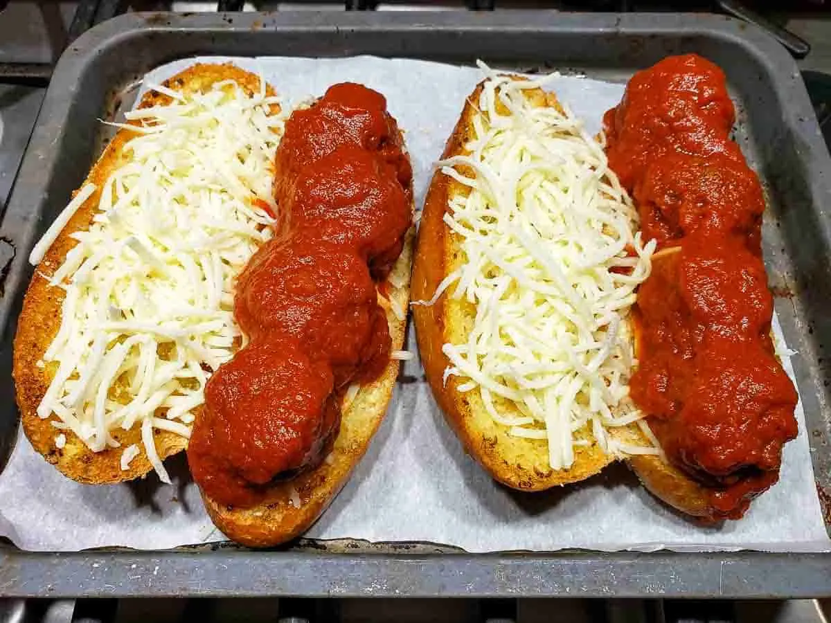 two toasted hoagie rolls filled with meatballs, spaghetti sauce, and mozzarella cheese.
