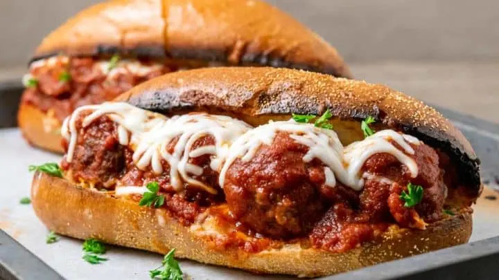 two meatball sandwiches on a baking sheet.