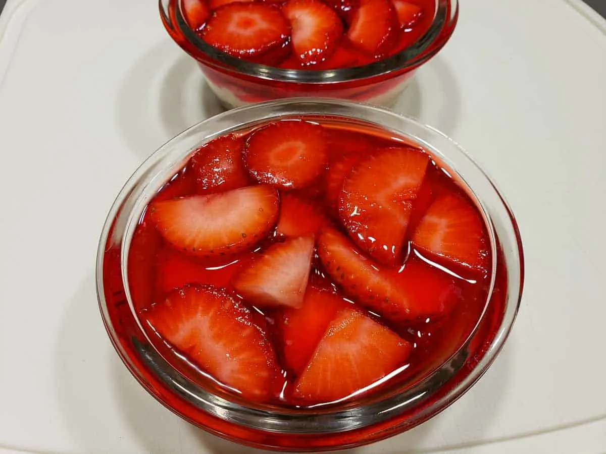 strawberry jello mixture layered on top of cream cheese layer in custard cups.