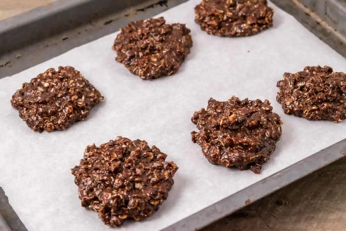 6 no bake cookies on parchment paper on a cookie sheet.