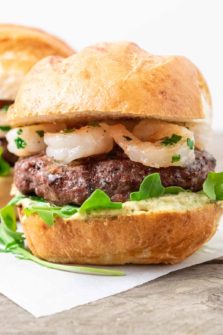 a surf n turf burger with beef patty, shrimp, arugula, and creamy pesto mayo.