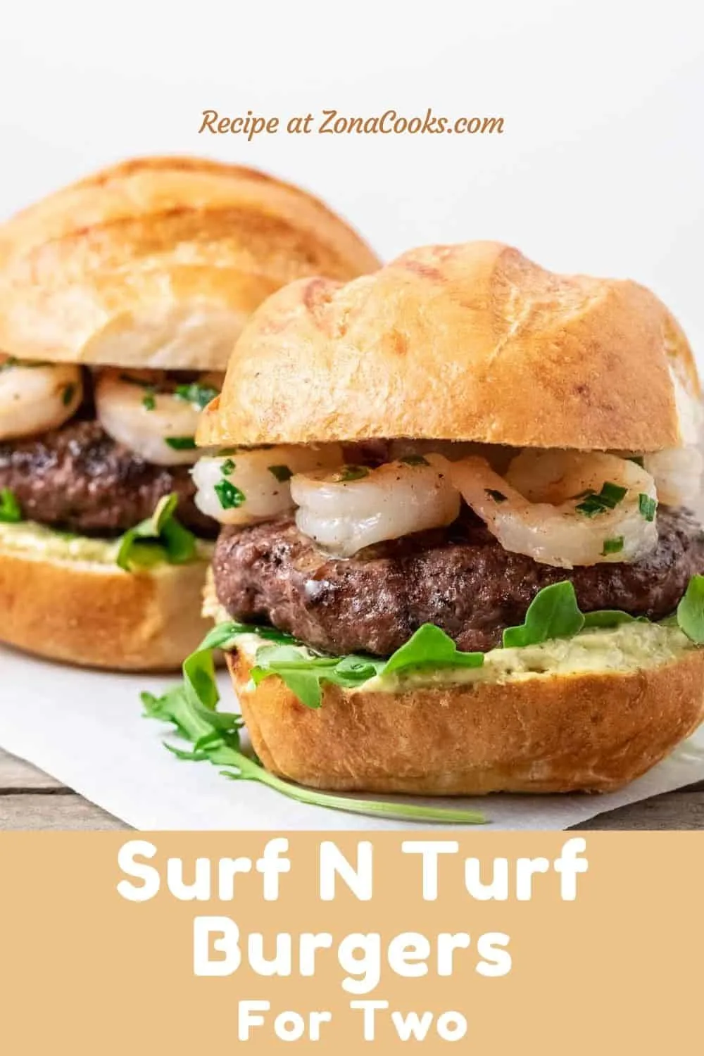 two burger buns filled with beef patties, arugula, pesto mayo, and seared shrimp and text reading recipe at zonacooks.com surf n turf burgers for two.
