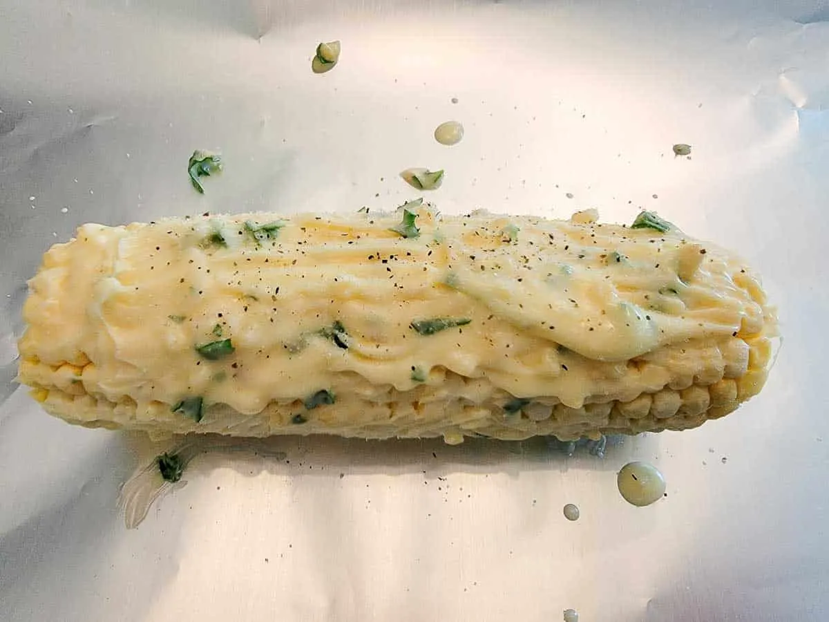 one ear of corn on the cob slathered with butter, garlic, salt, pepper, and parsley.