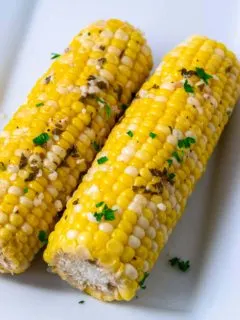 two pieces of Crock Pot Corn on the Cob on a plate.