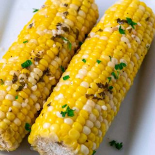 two pieces of Crock Pot Corn on the Cob on a plate.