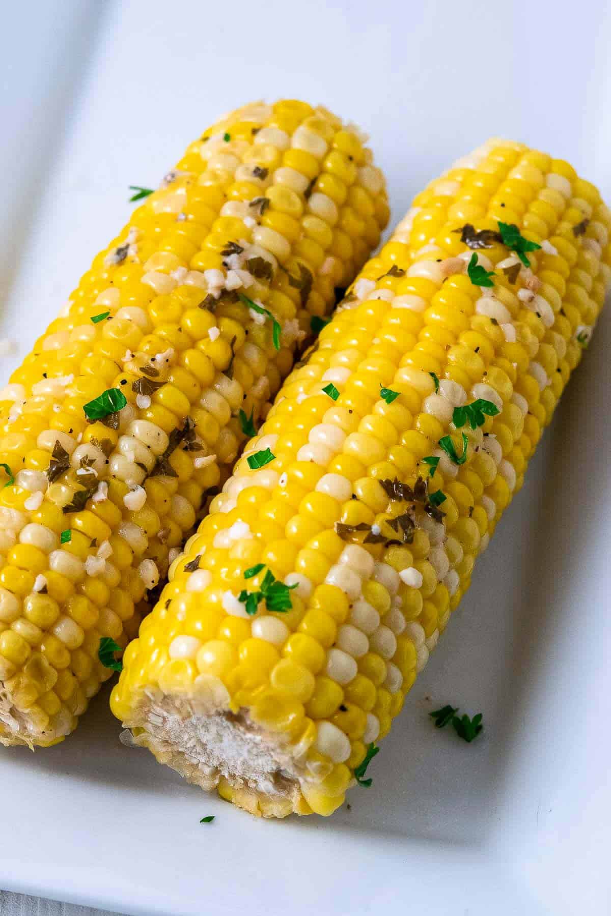 two pieces of Crock Pot Corn on the Cob on a plate.
