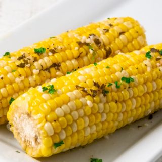 two ears of slow cooker corn on the cob on a plate.