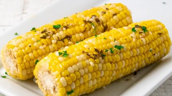 two ears of slow cooker corn on the cob on a plate.