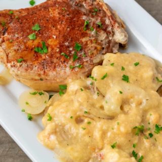 a plate filled with a Crock Pot Pork Chop and Au Gratin Potatoes.