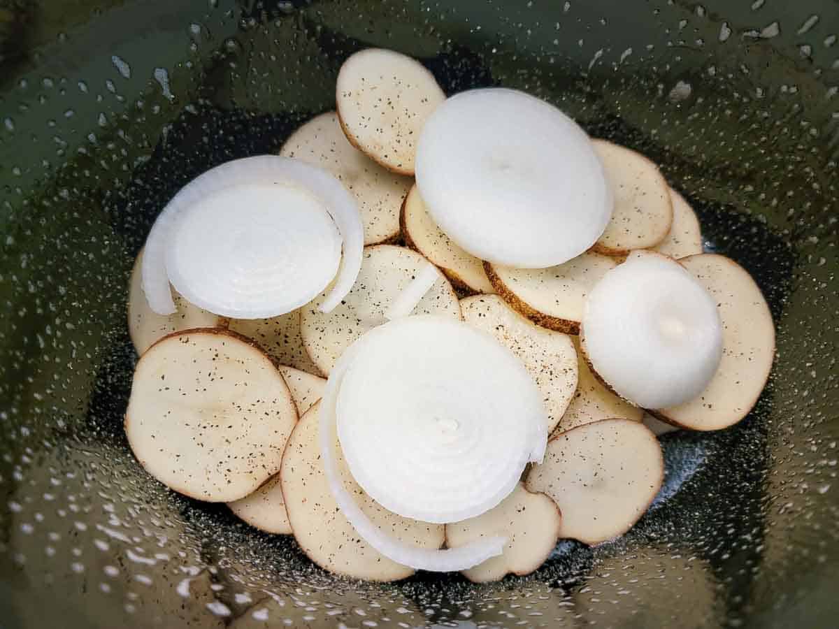 sliced potatoes and onions in a crock pot.