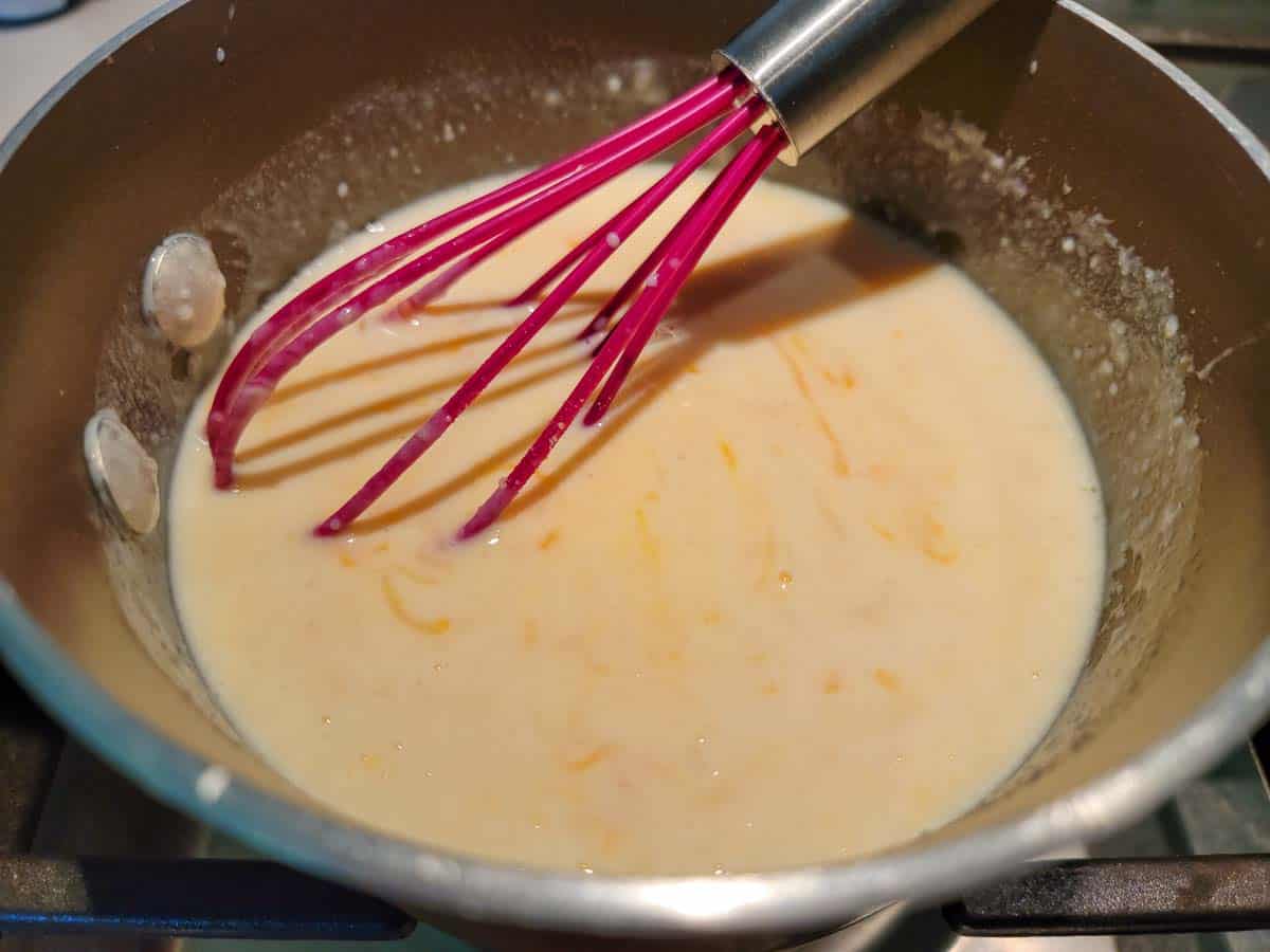 au gratin cheese sauce whisked in a sauce pan.