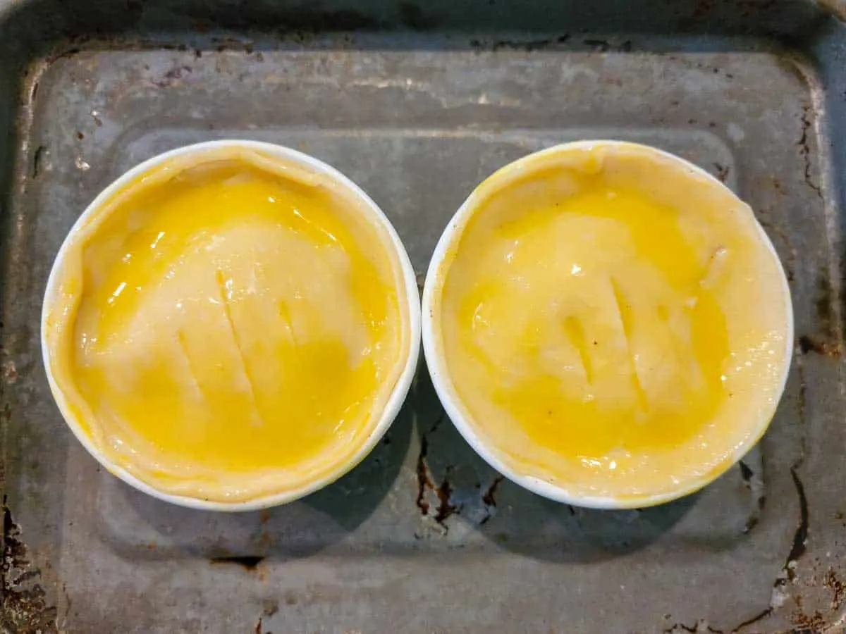 two mini pies brushed with egg wash.