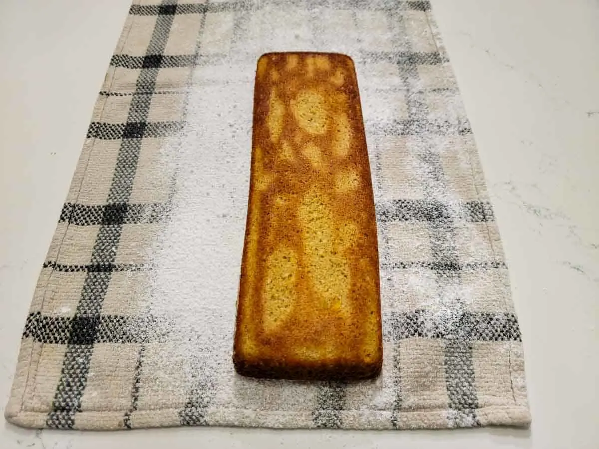 a pumpkin cake on a towel sprinkled with powdered sugar.