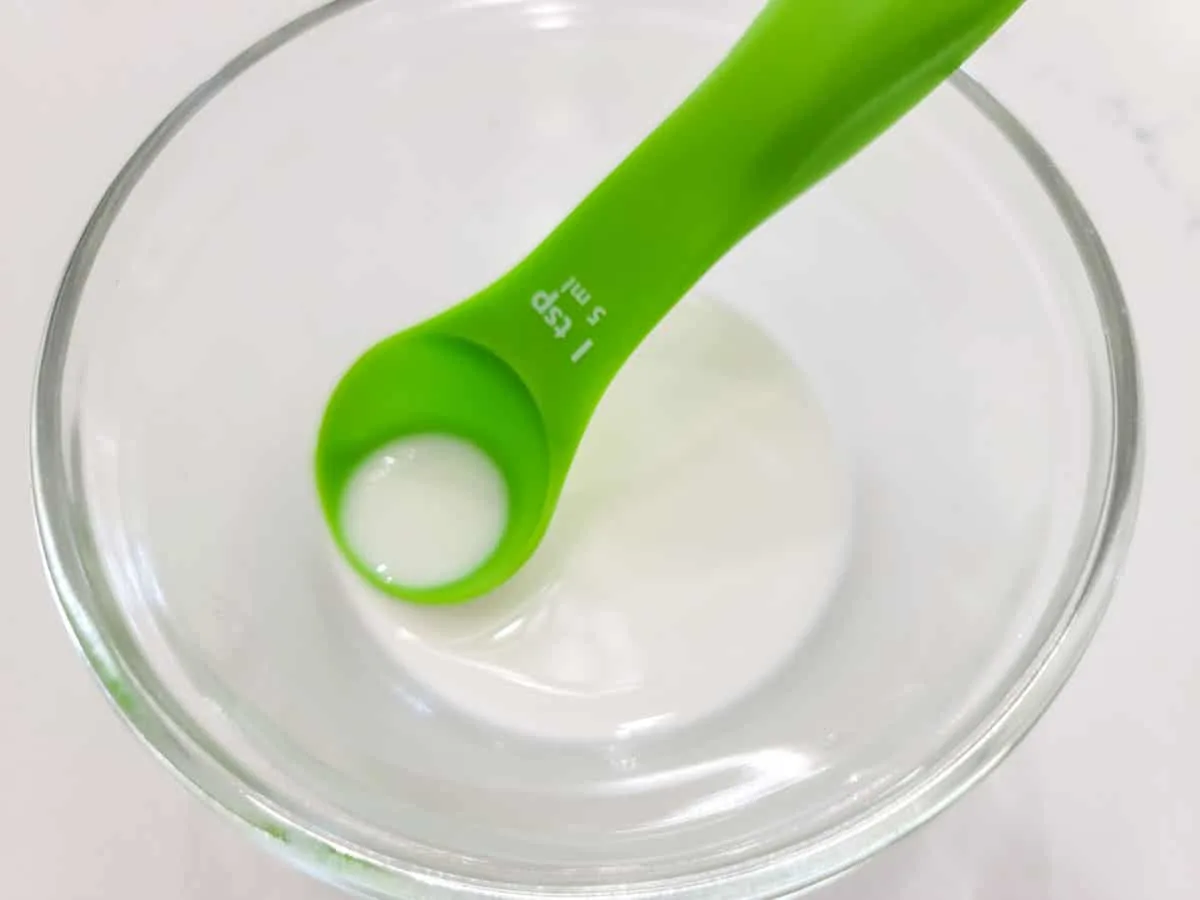 a cornstarch and water slurry in a bowl with a teaspoon.