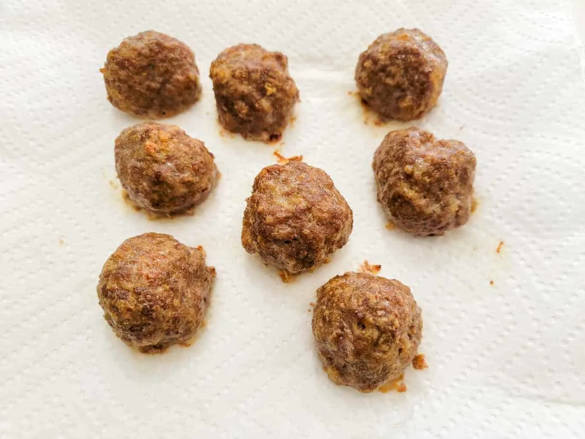 8 baked meatballs draining on paper towel.