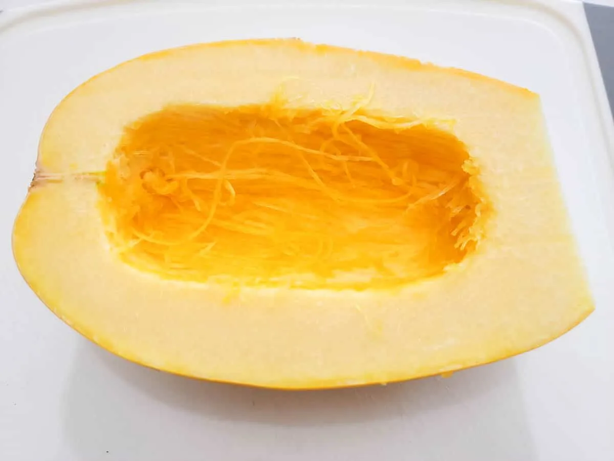 a half of a spaghetti squash on a cutting board.