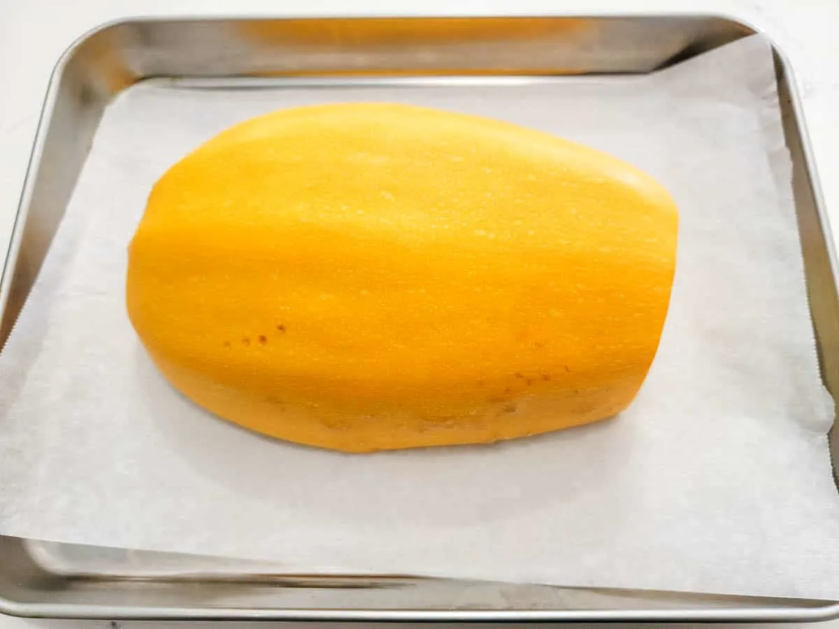 a spaghetti squash half cut side down on a baking sheet.