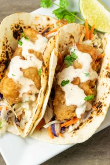 two Baja Fresh Fish Tacos with coleslaw on a plate.