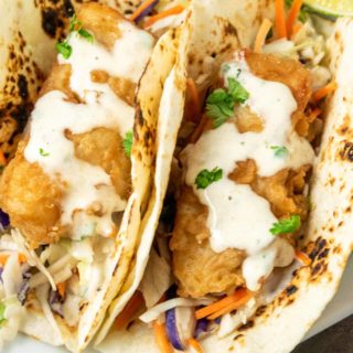 two Baja Fresh Fish Tacos with coleslaw on a plate.