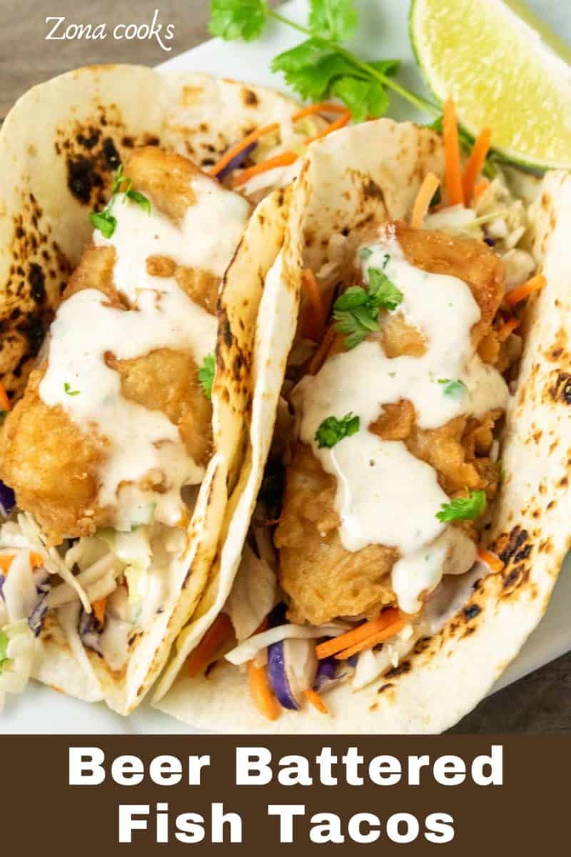 two Beer Battered Fish Tacos with coleslaw on a plate.