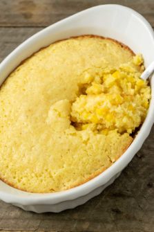 creamy corn casserole in a baking dish with a spoon.