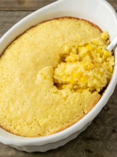 creamy corn casserole in a baking dish with a spoon.