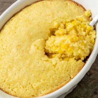 creamy corn casserole in a baking dish with a spoon.