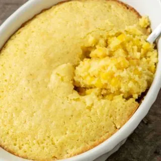 creamy corn casserole in a baking dish with a spoon.