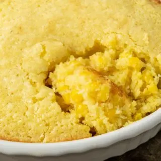 Corn pudding with a spoon in baking dish.