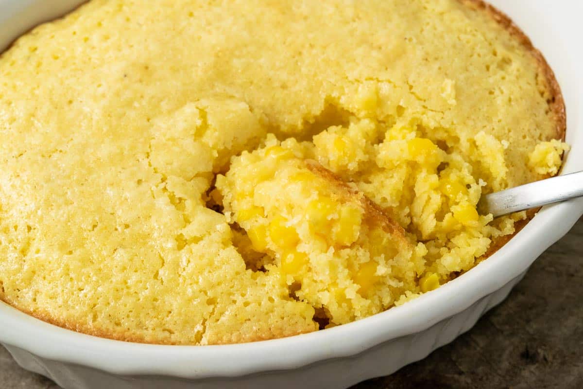Corn pudding with a spoon in baking dish.