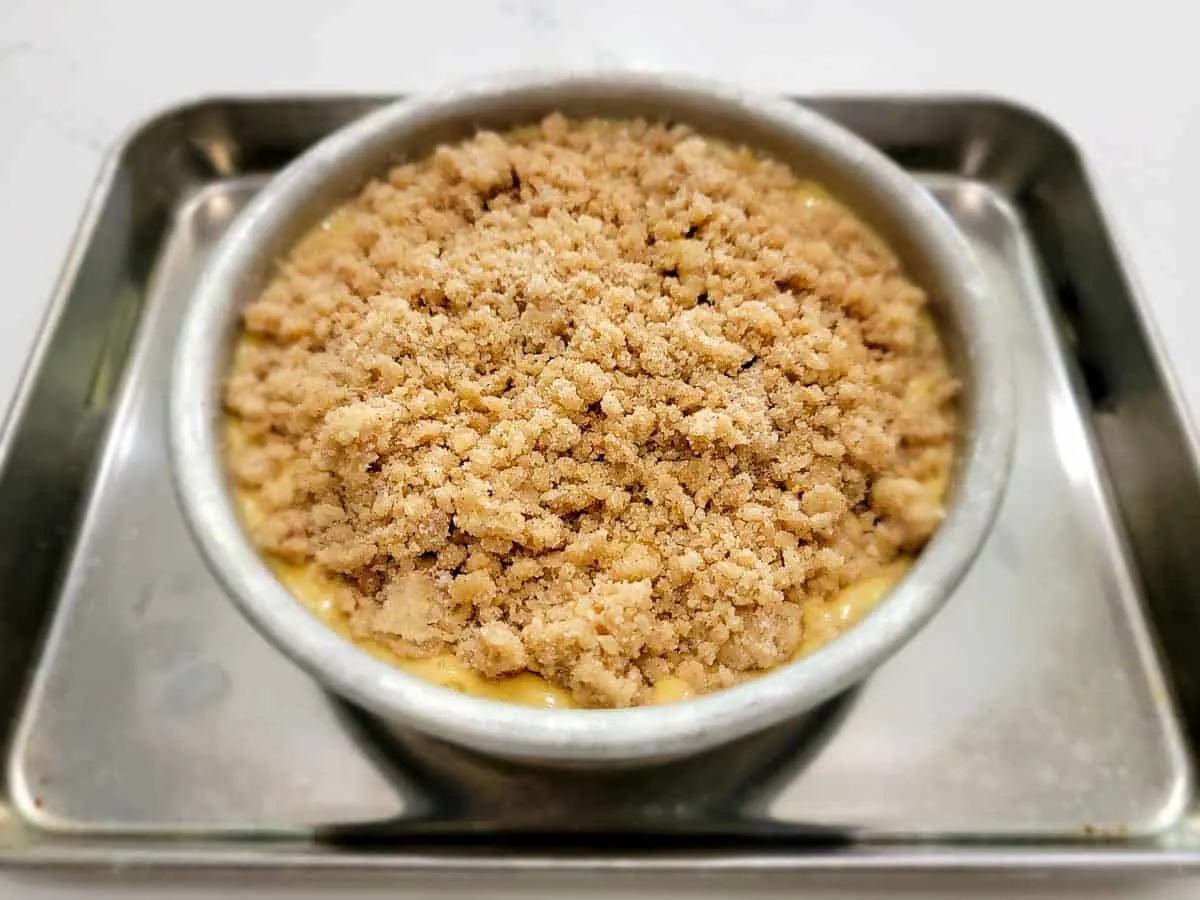 streusel crumble topping sprinkled onto the pumpkin cake batter in a 6 inch cake pan.