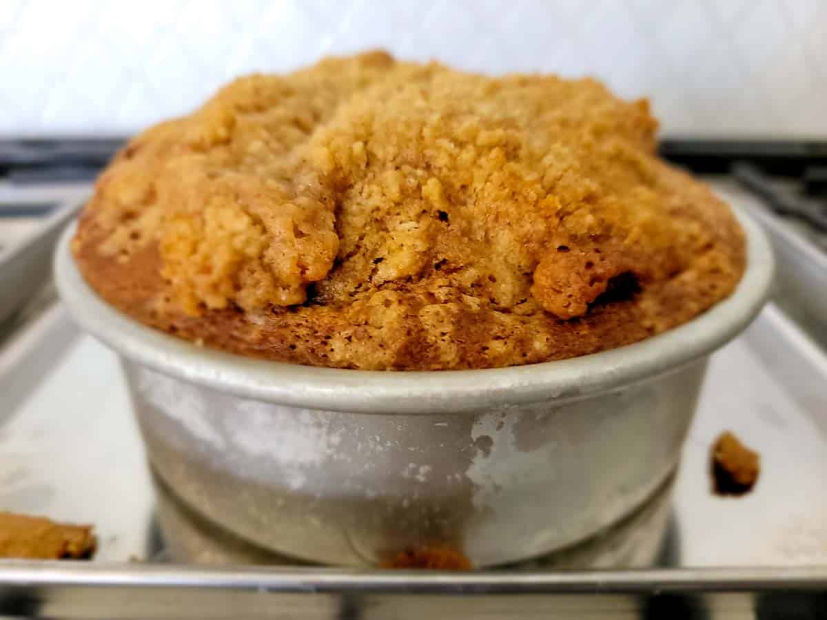 a small pumpkin coffee cake cooling in a 6 inch cake pan.