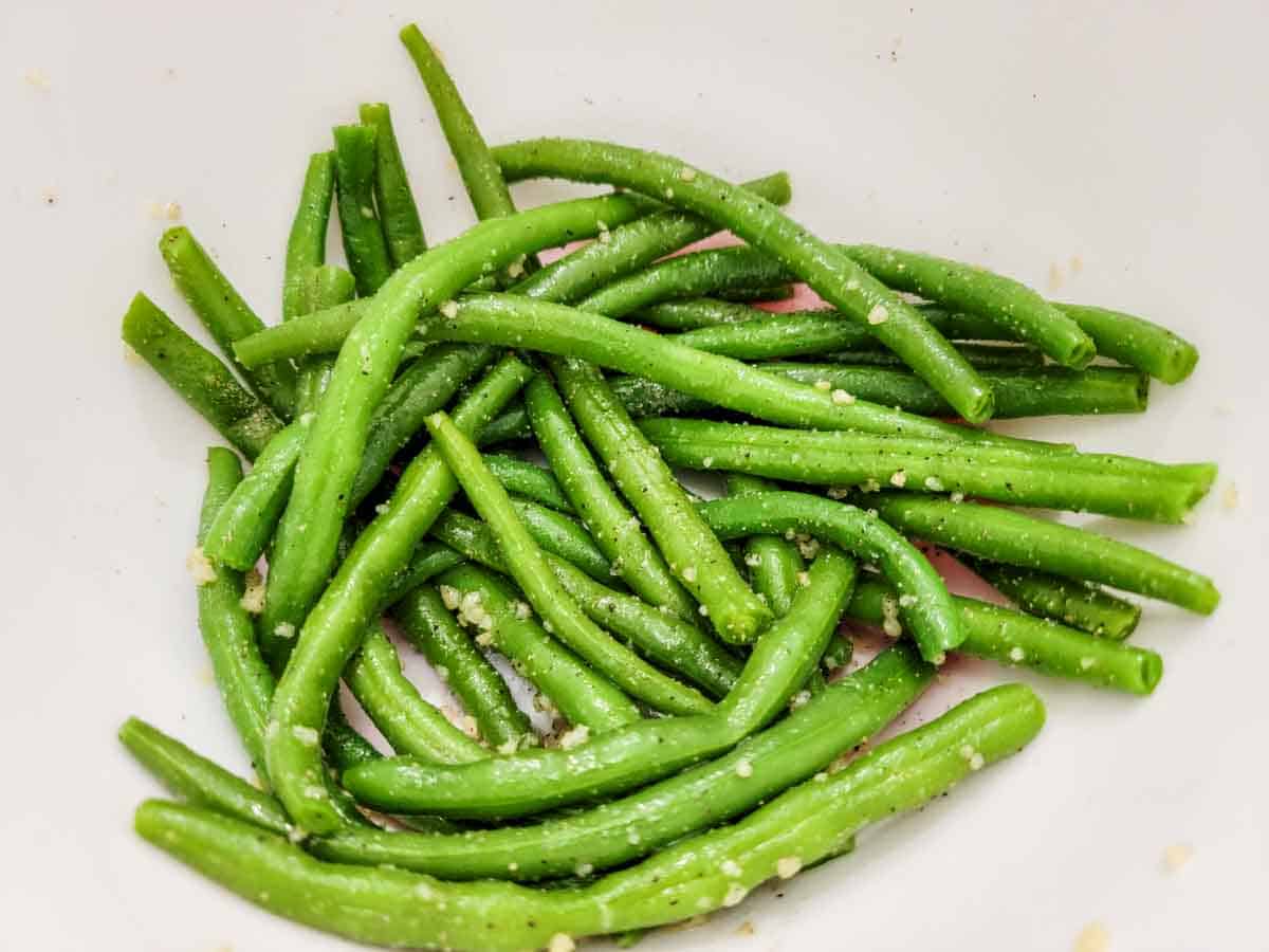 green beans, olive oil, garlic, salt and pepper in a bowl.