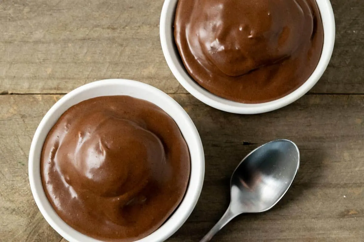 two small batch chocolate cakes with chocolate buttercream frosting in ramekin dishes.