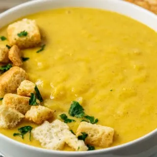 a bowl filled with Pumpkin Ginger Soup and croutons.
