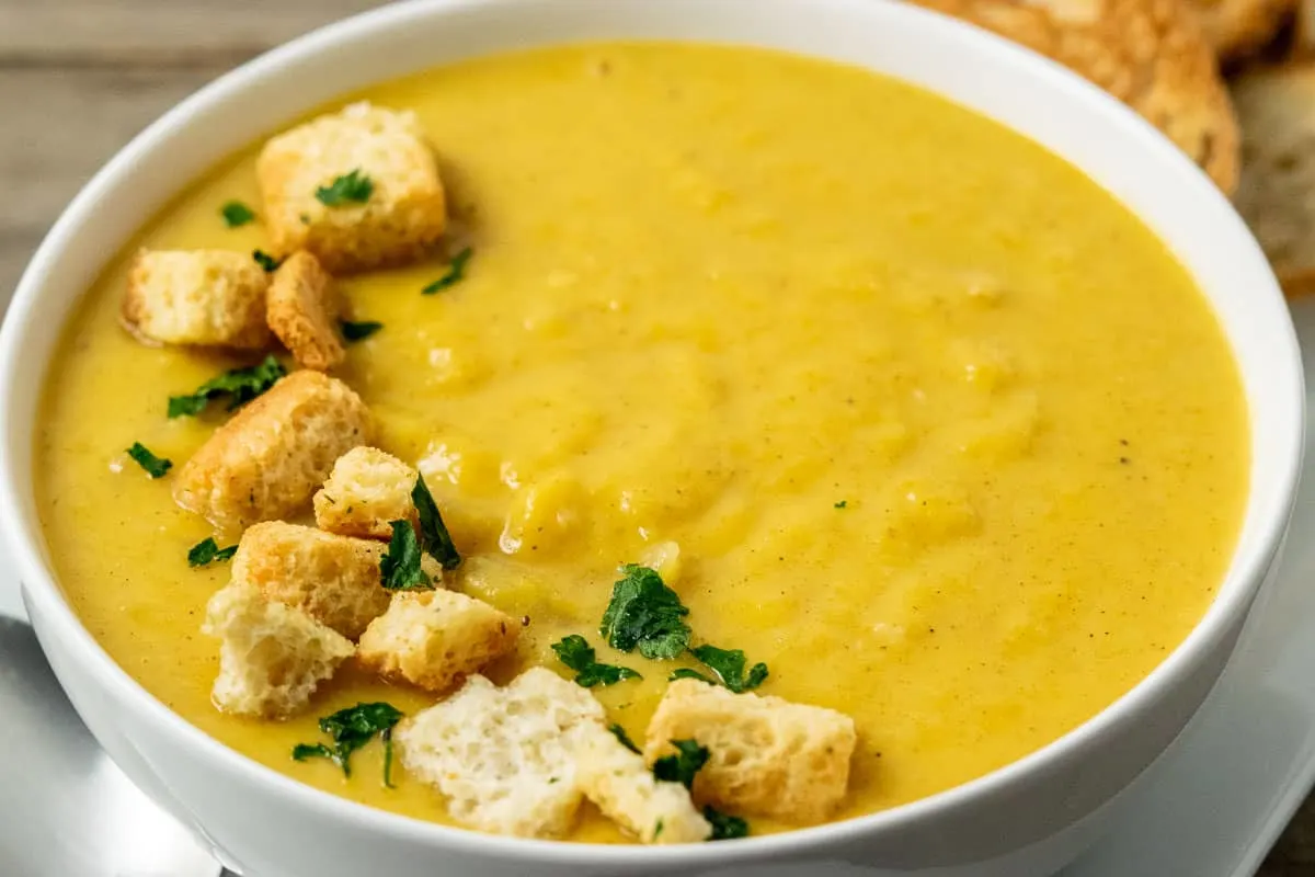 a bowl filled with Pumpkin Ginger Soup and croutons.