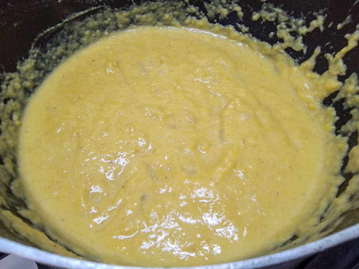 heavy cream stirred into pumpkin soup in a pan.