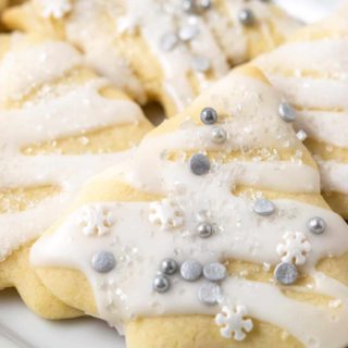 small batch of sugar cookies with icing and sprinkles on a tray.