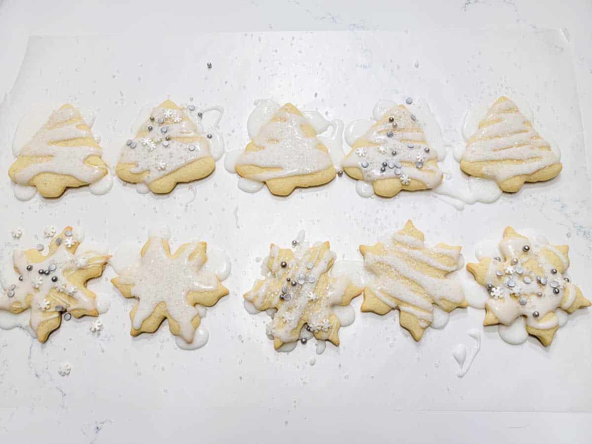 decorated cut-out sugar cookies with icing and sprinkles on wax paper.