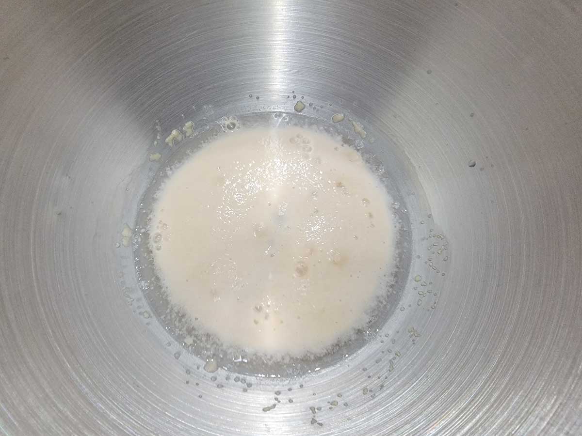 yeast, water, and sugar getting frothy in a bowl.