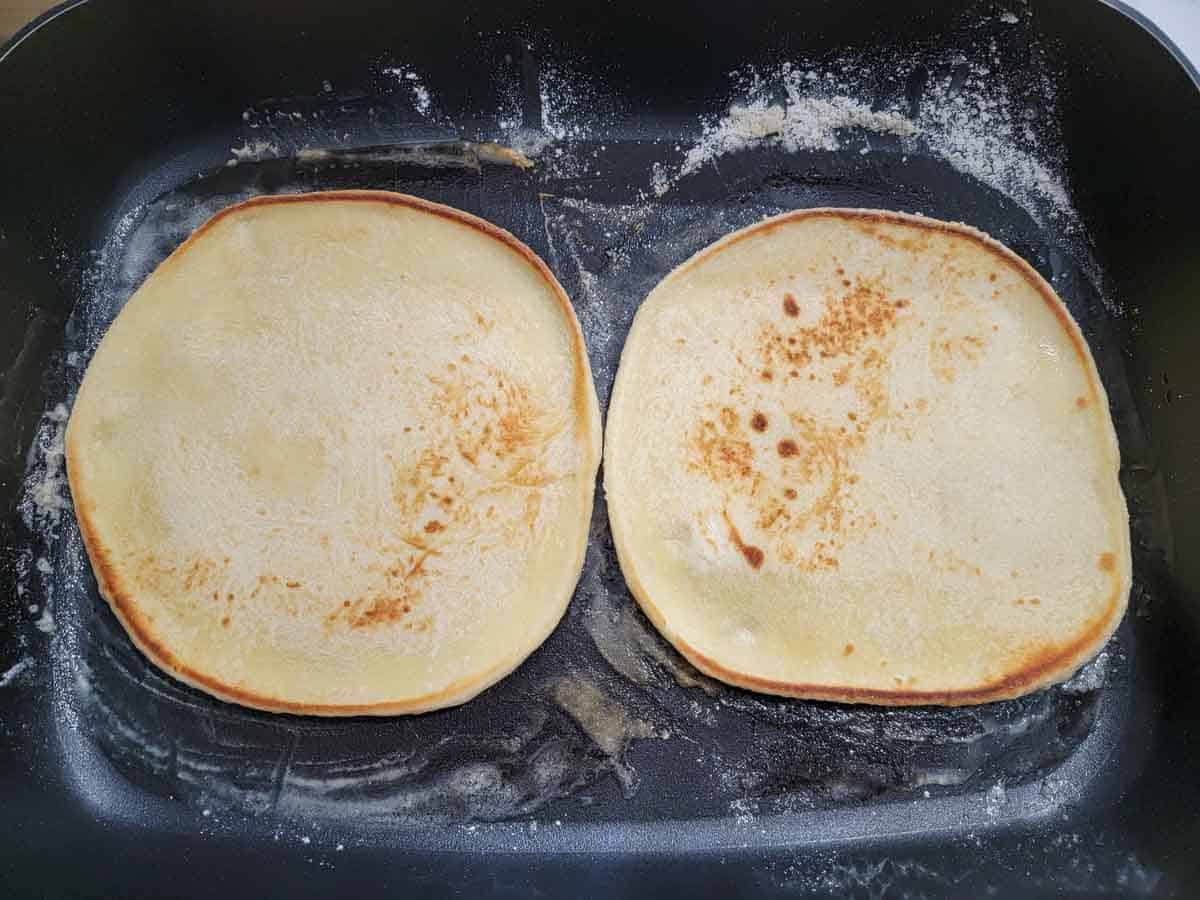 two flatbreads cooking in a skillet.