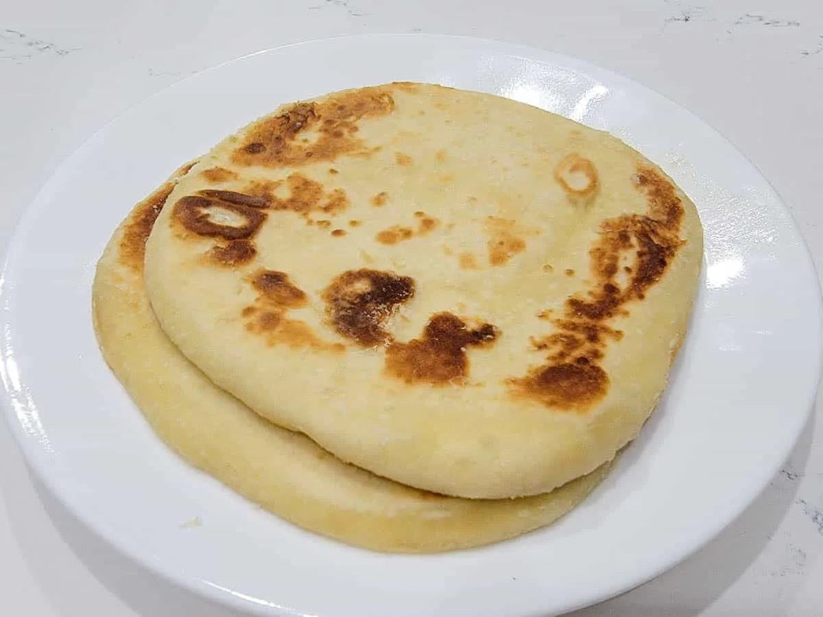 two cooked pieces of flatbread on a plate.