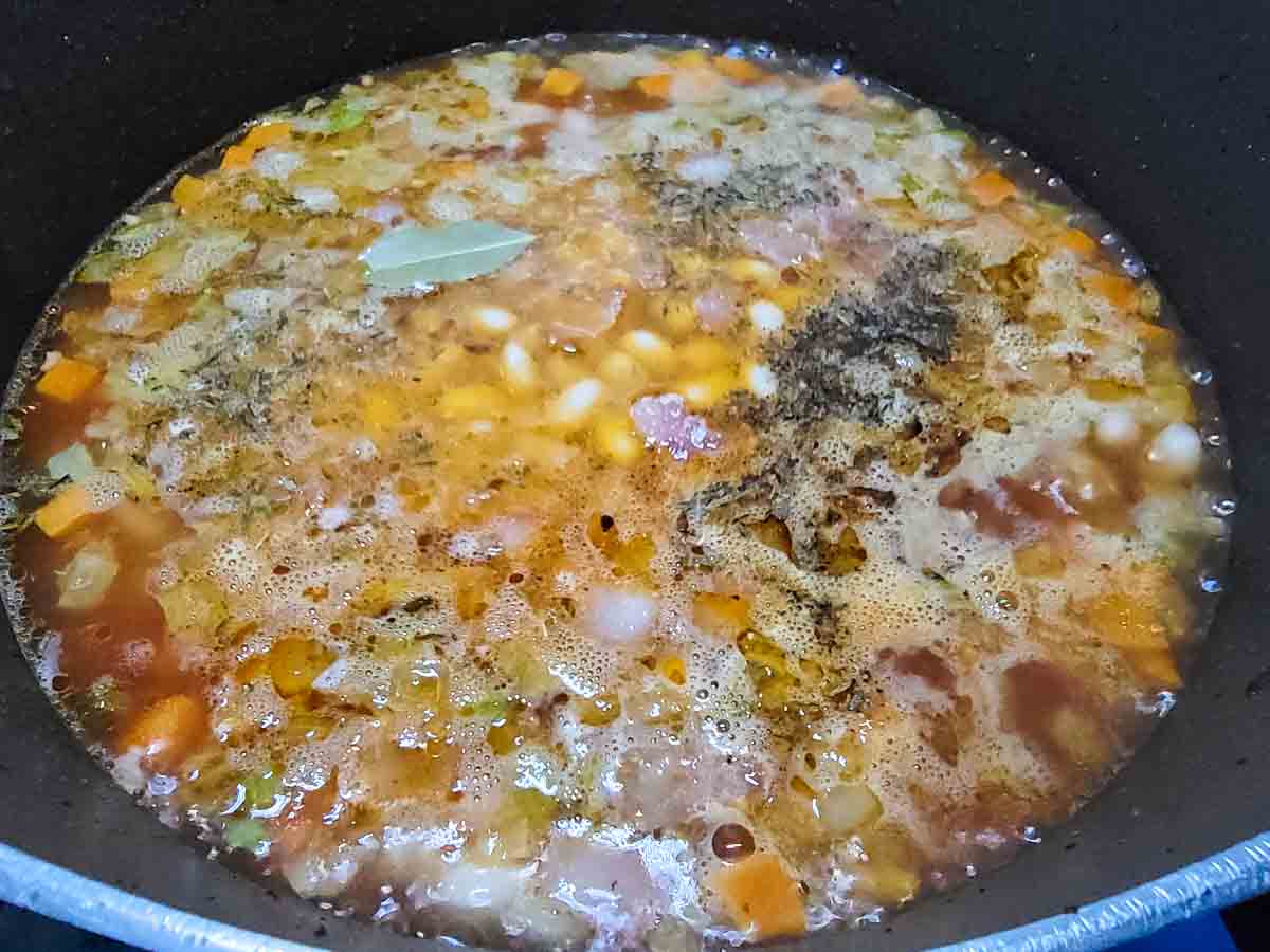 bean with bacon soup cooking in a pan.