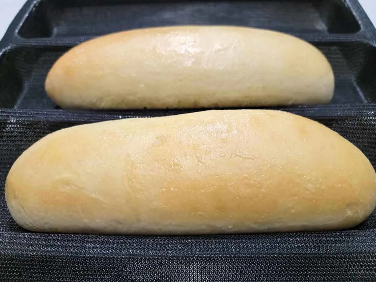 two fresh baked sub buns in a loaf mold.