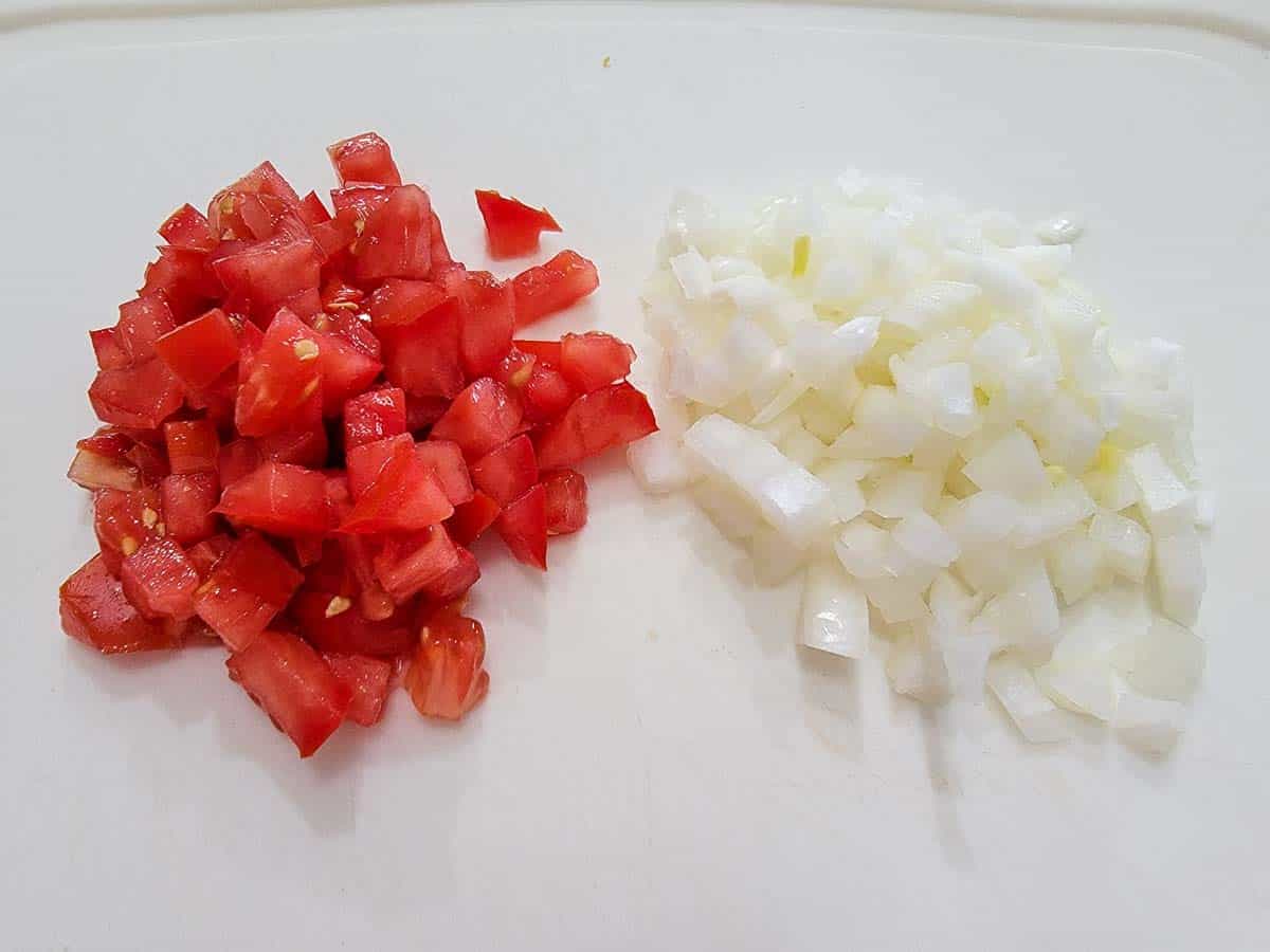 diced tomato and onion on a cutting board.