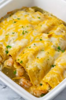 a casserole dish filled with 6 cheesy enchiladas.