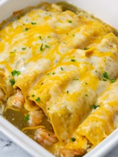 a casserole dish filled with 6 cheesy enchiladas.