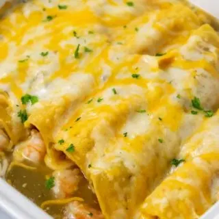 a casserole dish filled with 6 cheesy enchiladas.