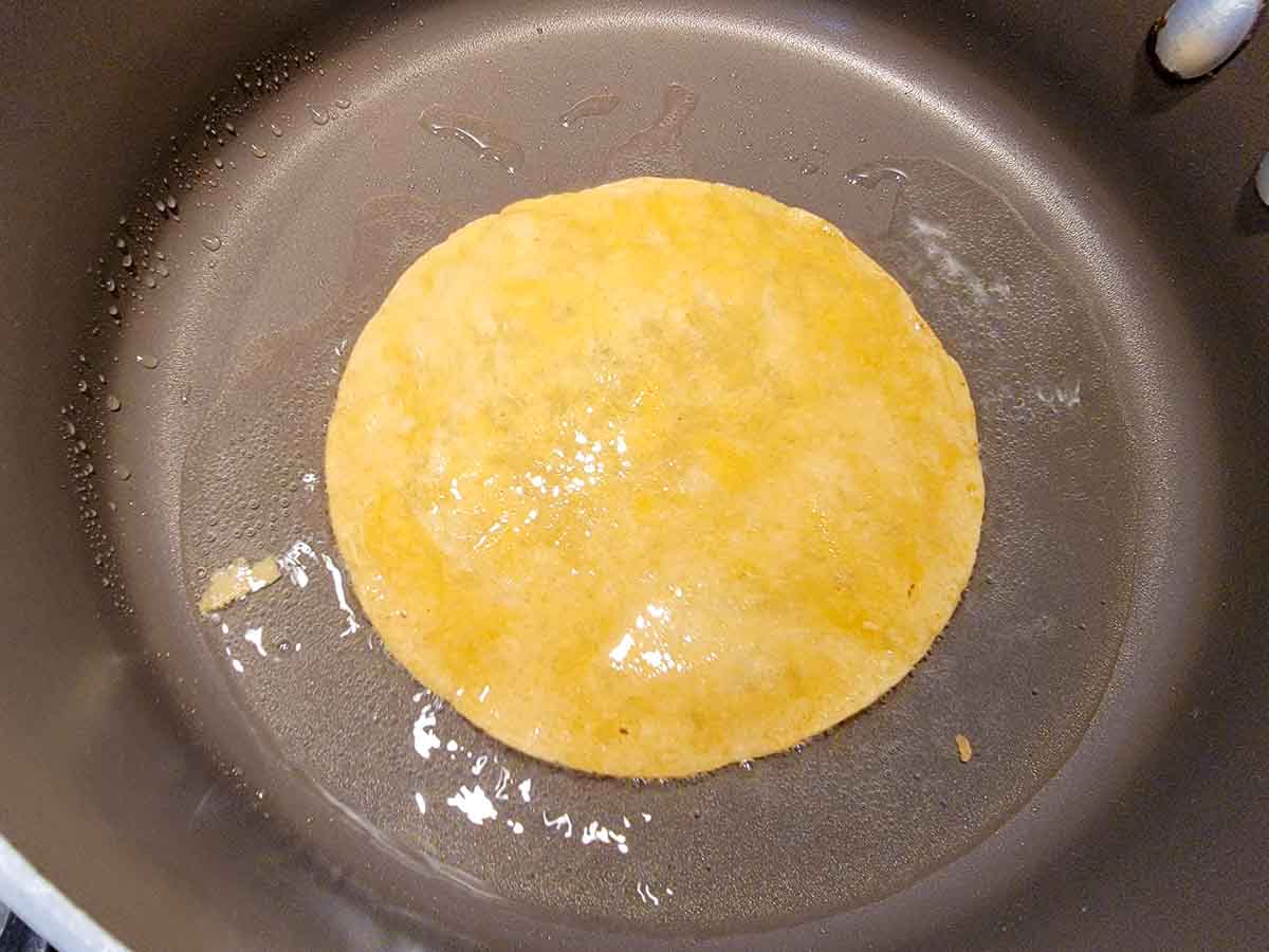 a corn tortilla frying in a pan.