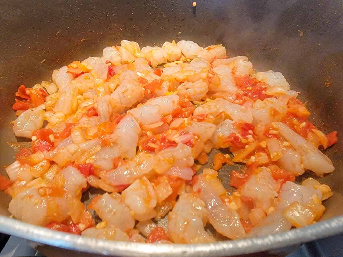 tomatoes, onions, garlic, shrimp and cumin cooking in a pan.